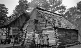 Three African American children in front of a cabin in Wilcox County, Alabama.