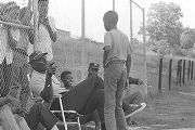 Man speaking to a young boy during a boys' baseball game, probably in Montgomery, Alabama.