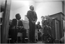 Richard Boone standing behind a podium after speaking to an audience at First Baptist Church in Eutaw, Alabama.