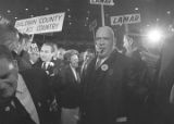 George and Lurleen Wallace walking through a crowd at a rally in the Municipal Auditorium in Birmingham, Alabama, during Lurleen's gubernatorial campaign.