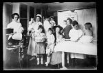 Baby Conference, October 7-8, 1921. Co. Health Center, San Luis Obispo, Calif. Left to right: Miss Pratt, dental hygienist; Marie A Jacobsen, R.N., Jr. R.C. school nurse; Miss Cleary, public health nurse, Bur. Child Hygiene; Miss Greenhood super., Dept. Dental Hygiene; Dr. Ethel M. Watters, dir. Bur. Child Hygiene. Lower row, boy in chair, two girls standing, mother with baby and child on table, all are of one family. Children were examined and had their teeth cleaned by Miss Pratt