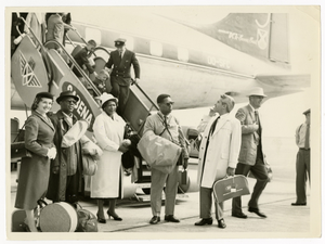 Musicians and others exiting Sabena airplane. Left to right: Stewardess, Roy Eldridge, Ella Fitzgerald, Dizzy Gillespie, Lou Levy, and Paul Smith, [Black-and-white photoprint.