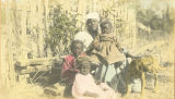 African American woman with three children and a dog in front of a wooden fence in rural Wilcox County, Alabama.