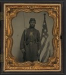 [Unidentified soldier in Union uniform and Company H cap with bayoneted musket, cap box, and Volunteer Maine Militia (VMM) belt buckle in front of American flag]