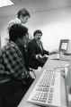 A College of Business Administration faculty member instructs two students in the computer lab