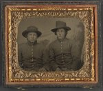 [Two unidentified soldiers in Union privates' uniforms in front of painted backdrop]