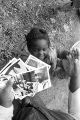 Wife and children of John Nixon standing in their yard in Autaugaville, Alabama, looking at photographs of themselves.