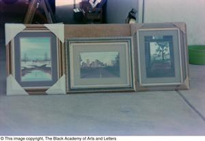 Photograph of three of James Edward Kemp's art works displayed outside of a garage