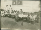 African-American children and women outside playing and eating at day nursery or play school