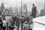 Man standing on a car and addressing the crowd outside Ebenezer Baptist Church at Martin Luther King, Jr.'s funeral.