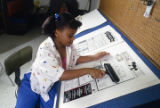 Eight-year-old Monica Bland working on the paste-up for the "Kids" page of the Tuskegee News at the newspaper's office in Tuskegee, Alabama.