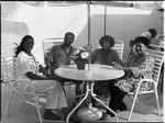 Three African American women and an African American man posing under a patio umbrella, Los Angeles, 1988