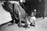 Percy Jones, Jr., kneeling on the floor with his daughter Barbara beside a bed in his home on Clayton Alley in Montgomery, Alabama.