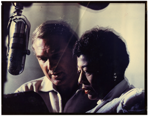 Ella Fitzgerald and Norman Granz at microphone : color photoprint.