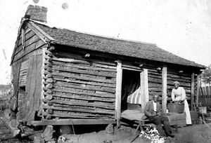 African-American man and woman in front of log house