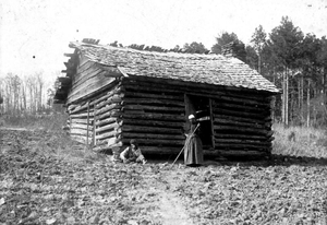 African-American man & woman in front of log house