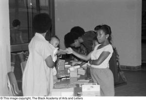 Photograph of baby holding onto a girl's finger