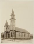 [African American man standing on sidewalk in front of church]