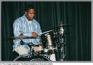 Photograph of a man playing a small drum set