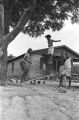 Elizabeth Ellis and Diane Foster playing on a make-shift seesaw in the dirt yard in front of a brick house in Newtown, a neighborhood in Montgomery, Alabama.