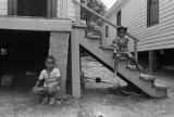 Little boy and girl sitting in front of a wooden house on Clayton Alley in Montgomery, Alabama.