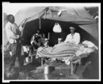 [African Americans in front of tent, with one man sitting up on bed, during a Mississippi River flood, Vicksburg National Military Park]