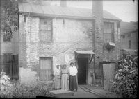 Three African American women in front of east side tenements, Pearl Street, Hartford