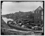 [Richmond, Va. Barges with African Americans on the Canal; ruined buildings beyond]