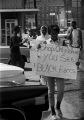 Protestors carrying signs while marching past businesses in downtown Prattville, Alabama, during a civil rights demonstration.