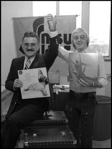 Leon Breeden and student clasp hands while holding albums