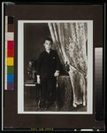 [African American boy, full-length portrait, standing,  facing front with left hand resting on table]