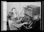 Production. Aircraft engines. Foreman F.I. Bowman shows Marietta Morgan how to operate this bomb-test machine used to test reconditioned spark plugs. A young Negro girl, Marietta, had formerly been a clerk in a meat market. Her lack of industrial experience, however, has been no handicap for her present war job in a large Midwest airplane plant. She's rapidly becoming a skilled and efficient machine operator. Melrose Park, Buick plant