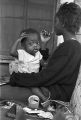 Young woman holding a baby while sitting on the porch of a house in Little Korea, a neighborhood in Birmingham, Alabama.