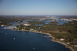 An October 2017 aerial view of New Castle, New Hampshire, with the historic seaport of Portsmouth, the largest city along the shortest coastline (18 miles) of any U.S. state, in the distance. The large white building with a red roof is the 1874 Wentworth-by-the-Sea Hotel, a historic grand resort hotel in New Castle. Now managed by Marriott, it is one of a handful of the state's surviving Gilded Age grand hotels, and the last located on the seacoast