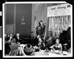 Charlotta Bass and other guests listen to a musician performing at a birthday party for the Independent Progressive Party of California, circa 1949, Los Angeles