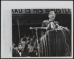 [Elijah Muhammad, leader of the Black Muslims, addressing a convention in Chicago; boxer Muhammad Ali sits on the left with other men]