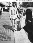 Marston's Department store doorman Charles Walker holding open the door of an automobile outside the store