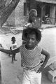 Diane Foster standing beside a tree in the dirt front yard of a brick house in Newtown, a neighborhood in Montgomery, Alabama.