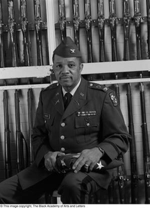 Col. Joe D. Sasser posing in front of drill rifles #2