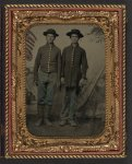 [Two unidentified young soldiers in Union uniforms in front of painted backdrop showing military camp]