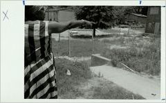 Eva Davis points at overgrown grass in the East Lake Meadows apartment complex, June 29, 1989