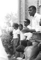 Stokely Carmichael and others, standing against the wall of a brick church building in Prattville, Alabama, during a meeting of the Autauga County Improvement Association.