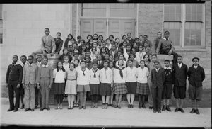 Group of children, on steps in front of building, girls all in middle, boys on side] [acetate film photonegative