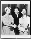 [Actresses Maureen O'Hara and Dorothy Dandridge join hands, outside courtroom, as if to seal a pact against Confidential Magazine, while Maureen's brother, James FitzSimons, looks on]