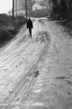 Man walking on a muddy street.