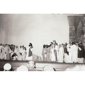 Bearded actor speaks to a crowd gathered around him on stage