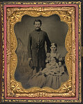 [Unidentified soldier in Union uniform with wife and baby daughter in front of painted backdrop showing military camp]