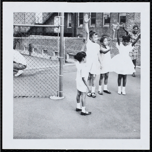 Girls standing in a semicircle and raising their hands during a Little Sister Contest