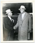 Joe Louis and Frederick M. Roberts are shaking hands in front of airplane