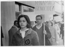 Mississippi State Sovereignty Commission photograph of Barbara Ashley and an unidentified African American man holding a protest sign standing in the foreground of a crowd of demonstrators during an Anti-Vietnam War demonstration protesting Secretary of Defense Robert McNamara's visit to Jackson, Mississippi, 1967 February 24